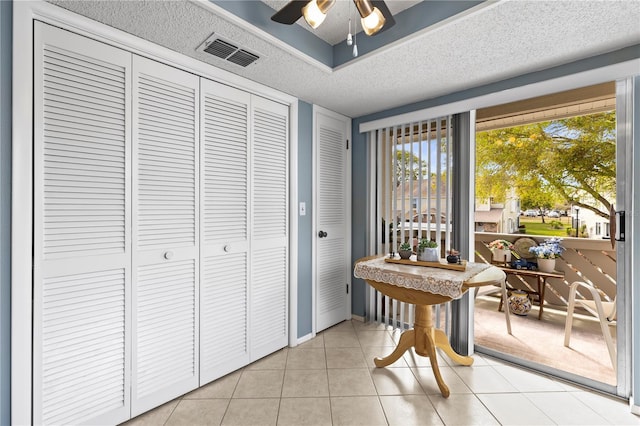 interior space featuring light tile patterned floors, baseboards, visible vents, ceiling fan, and a textured ceiling