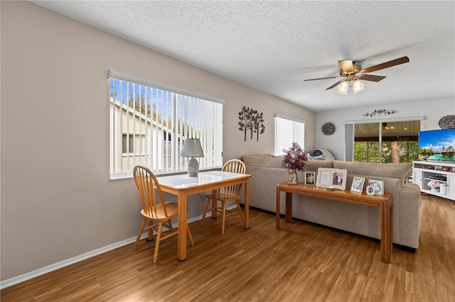 living area with a textured ceiling, ceiling fan, wood finished floors, and baseboards