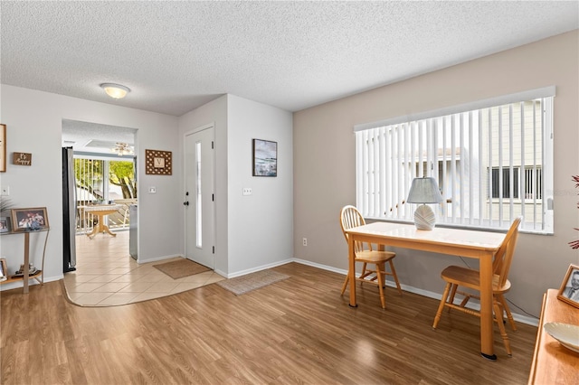 entryway featuring light wood finished floors, baseboards, and a textured ceiling