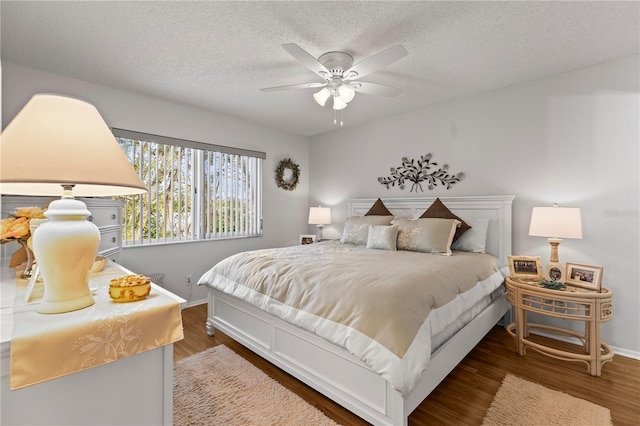 bedroom featuring ceiling fan, a textured ceiling, baseboards, and wood finished floors