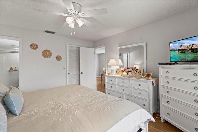 bedroom with visible vents, dark wood finished floors, a textured ceiling, and ceiling fan