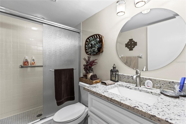 full bathroom featuring a stall shower, vanity, and toilet