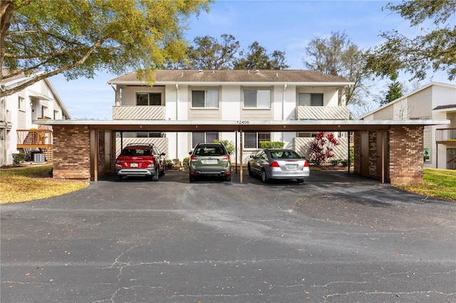 townhome / multi-family property featuring covered parking, brick siding, and stucco siding