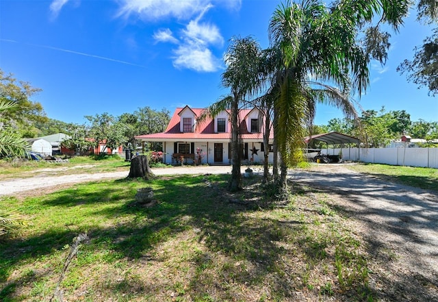 cape cod home featuring driveway, fence, a front lawn, and a carport