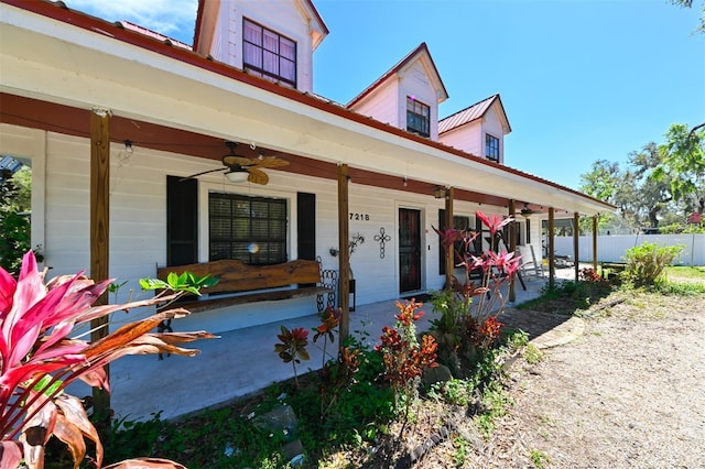 entrance to property featuring covered porch, fence, and a ceiling fan