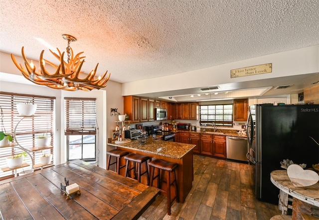 dining space with an inviting chandelier, visible vents, dark wood finished floors, and a textured ceiling