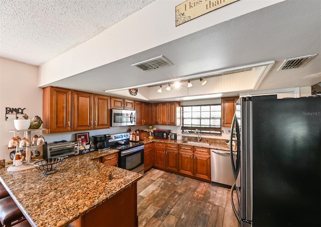 kitchen with a peninsula, visible vents, appliances with stainless steel finishes, and brown cabinets