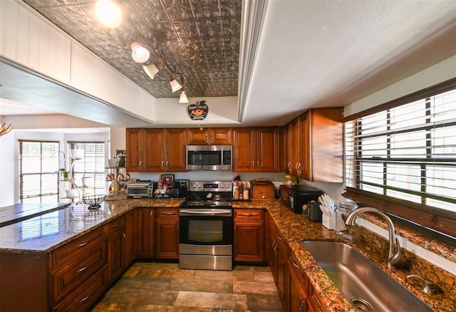 kitchen featuring an ornate ceiling, a tray ceiling, brown cabinets, stainless steel appliances, and a sink