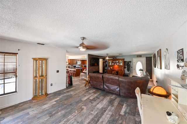 living area featuring ceiling fan, dark wood-style flooring, a textured ceiling, and visible vents