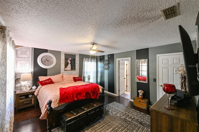 bedroom featuring ceiling fan, a textured ceiling, visible vents, and wood finished floors