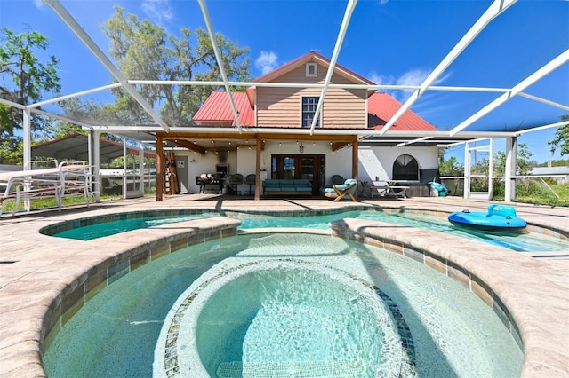 view of pool with a patio, glass enclosure, and a pool with connected hot tub