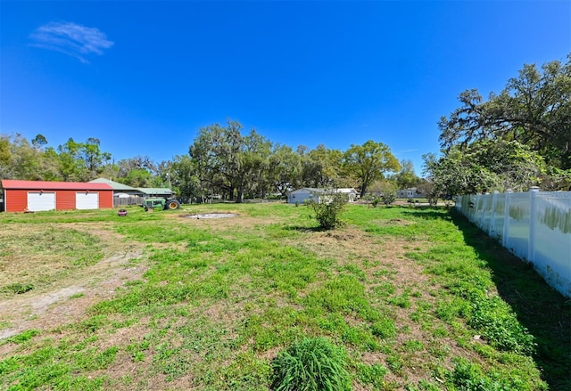 view of yard with driveway, a detached garage, and fence