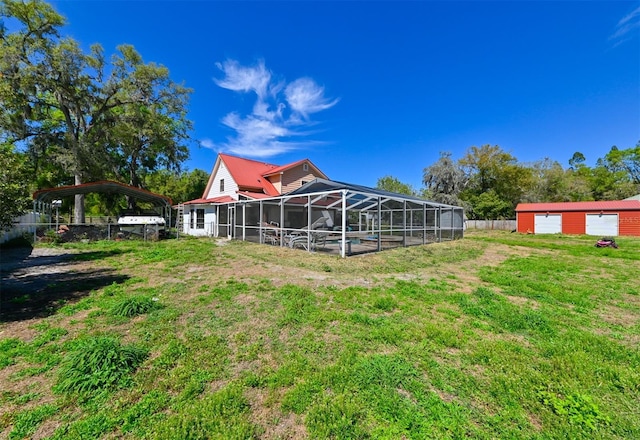 back of house featuring metal roof, glass enclosure, fence, a lawn, and a carport