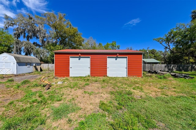 detached garage featuring a shed and fence