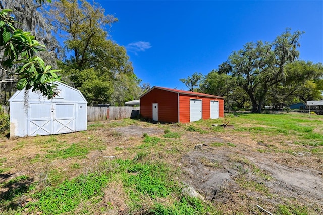 view of yard with a storage shed, a detached garage, fence, and an outdoor structure