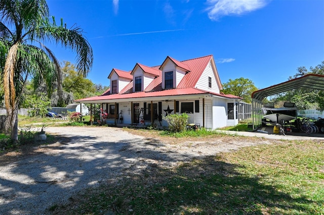 view of front of property featuring metal roof, driveway, and a porch