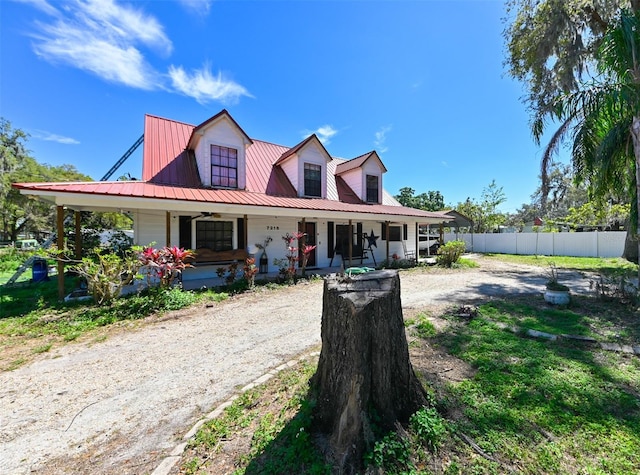 view of front of house with covered porch, fence, and metal roof