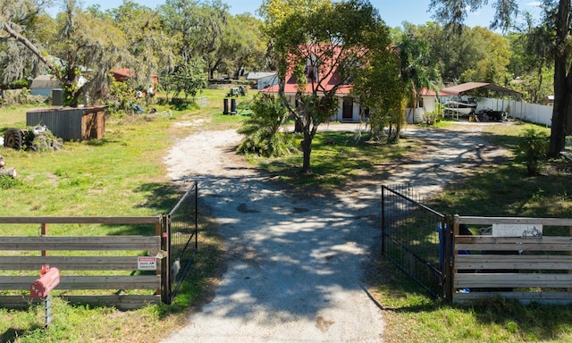 view of street with dirt driveway, a gated entry, and a gate