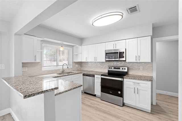 kitchen with a sink, stainless steel appliances, open shelves, a peninsula, and white cabinets