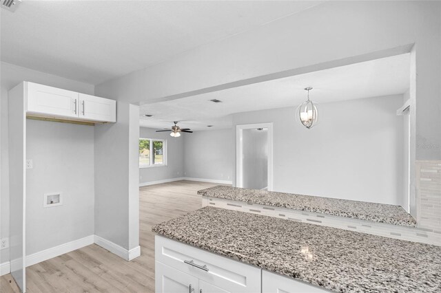 kitchen with ceiling fan, white cabinetry, light stone countertops, and light wood-style floors