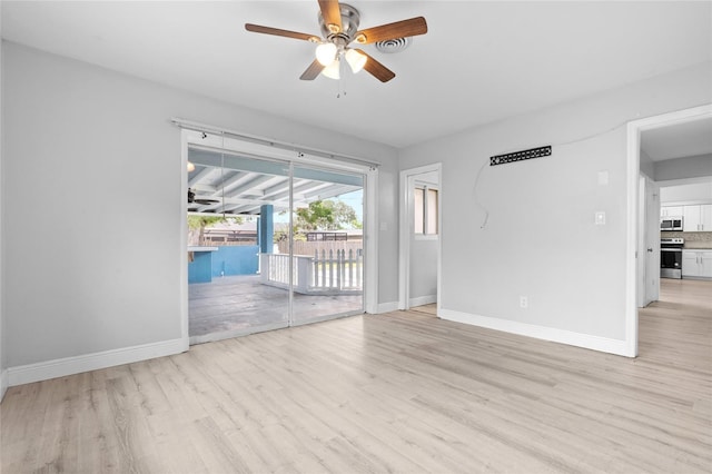 empty room featuring light wood finished floors, a ceiling fan, and baseboards