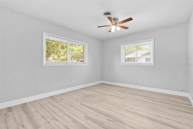 spare room featuring a ceiling fan, visible vents, baseboards, and light wood-style floors