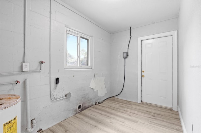 clothes washing area with light wood-type flooring and water heater