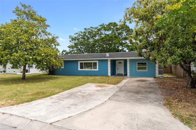 single story home with concrete driveway, a front lawn, fence, and a shingled roof