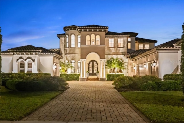 mediterranean / spanish-style home with stucco siding, french doors, and decorative driveway