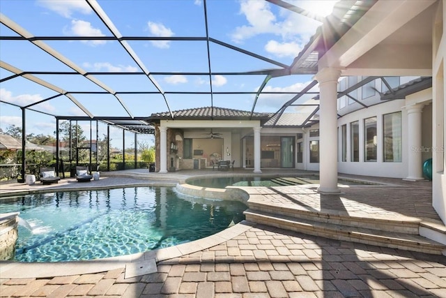 view of swimming pool with glass enclosure, a pool with connected hot tub, ceiling fan, and a patio area