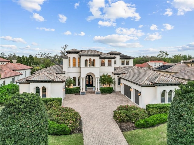 mediterranean / spanish house featuring a tile roof, a garage, driveway, and stucco siding