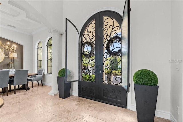 foyer featuring stone tile floors, a notable chandelier, french doors, and baseboards