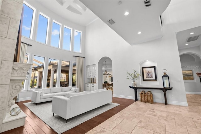 living area with wood finished floors, visible vents, arched walkways, and baseboards