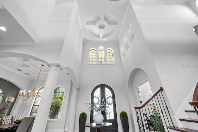 entryway featuring a high ceiling, stairway, arched walkways, and ornamental molding