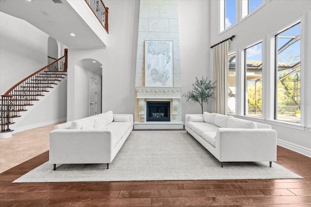 living room featuring a healthy amount of sunlight, baseboards, stairway, hardwood / wood-style floors, and arched walkways