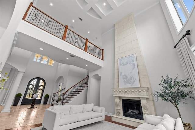 living area featuring stairway, a fireplace, a towering ceiling, wood finished floors, and arched walkways