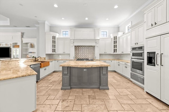 kitchen with a warming drawer, ornamental molding, stone tile flooring, stainless steel appliances, and white cabinets