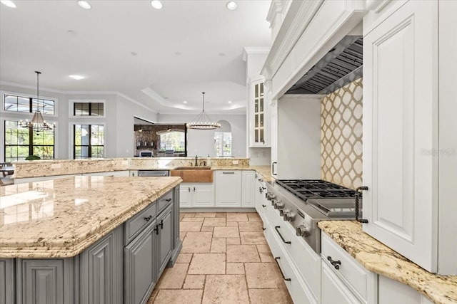 kitchen with recessed lighting, gray cabinets, ornamental molding, stone tile flooring, and custom range hood