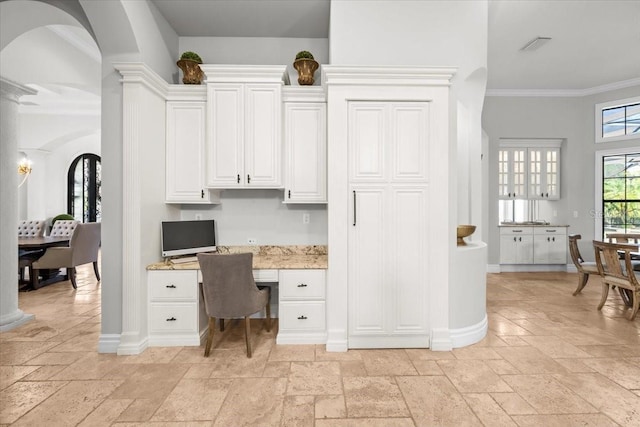 home office with stone tile floors, built in study area, ornate columns, and ornamental molding