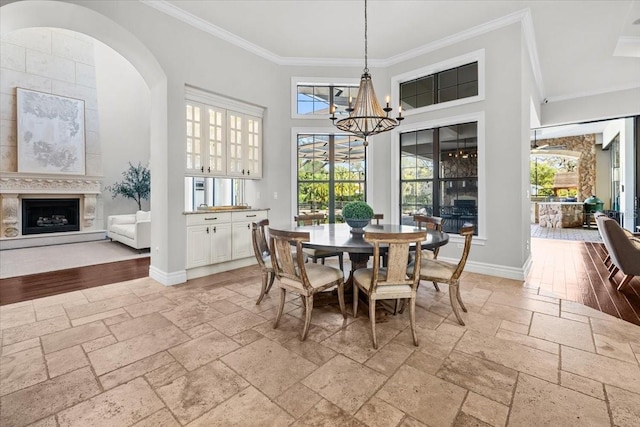 dining space featuring baseboards, an inviting chandelier, stone tile flooring, and crown molding