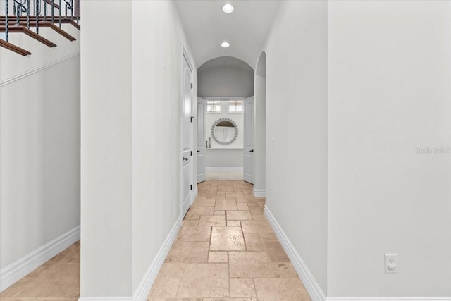 hallway featuring recessed lighting, baseboards, arched walkways, and stone tile floors