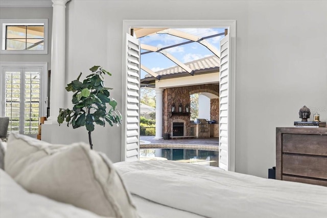 bedroom with a stone fireplace, access to outside, and arched walkways