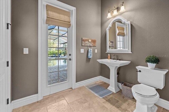 bathroom with baseboards, toilet, and stone tile floors