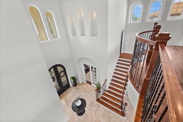 stairs with french doors, arched walkways, and a towering ceiling