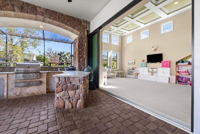 view of patio with an outdoor kitchen, a lanai, and a grill