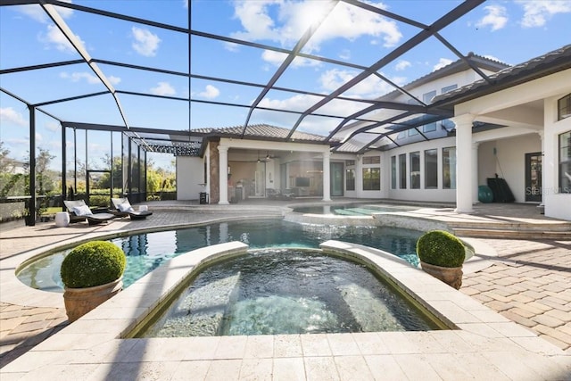 view of pool featuring glass enclosure, a pool with connected hot tub, and a patio area