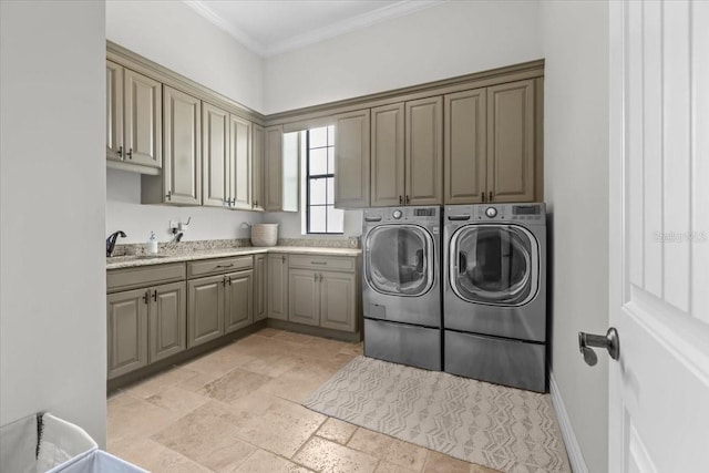 laundry area featuring washing machine and dryer, ornamental molding, stone tile floors, cabinet space, and a sink