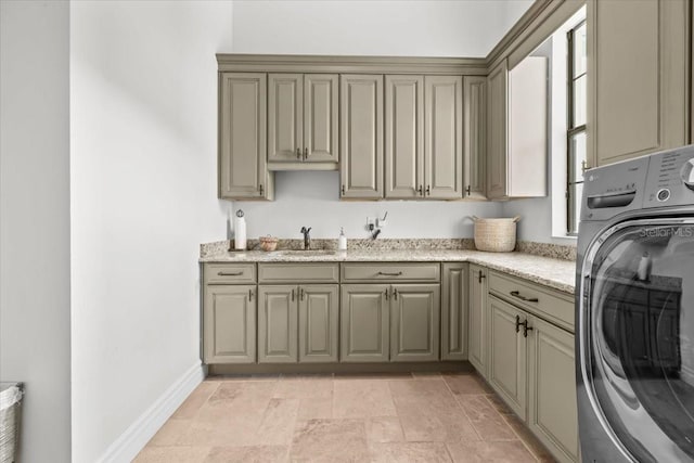 laundry room with a sink, baseboards, washer / clothes dryer, and cabinet space