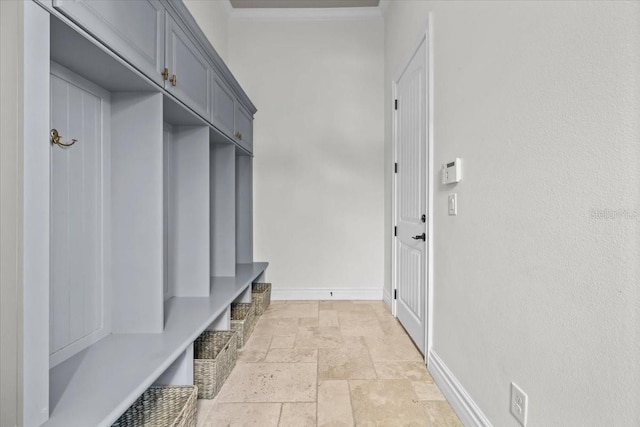 mudroom featuring crown molding, stone tile floors, and baseboards