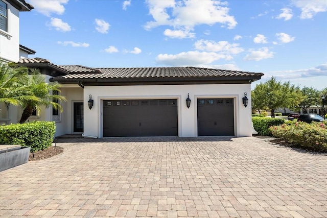 view of front of property featuring decorative driveway, a garage, stucco siding, and a tiled roof